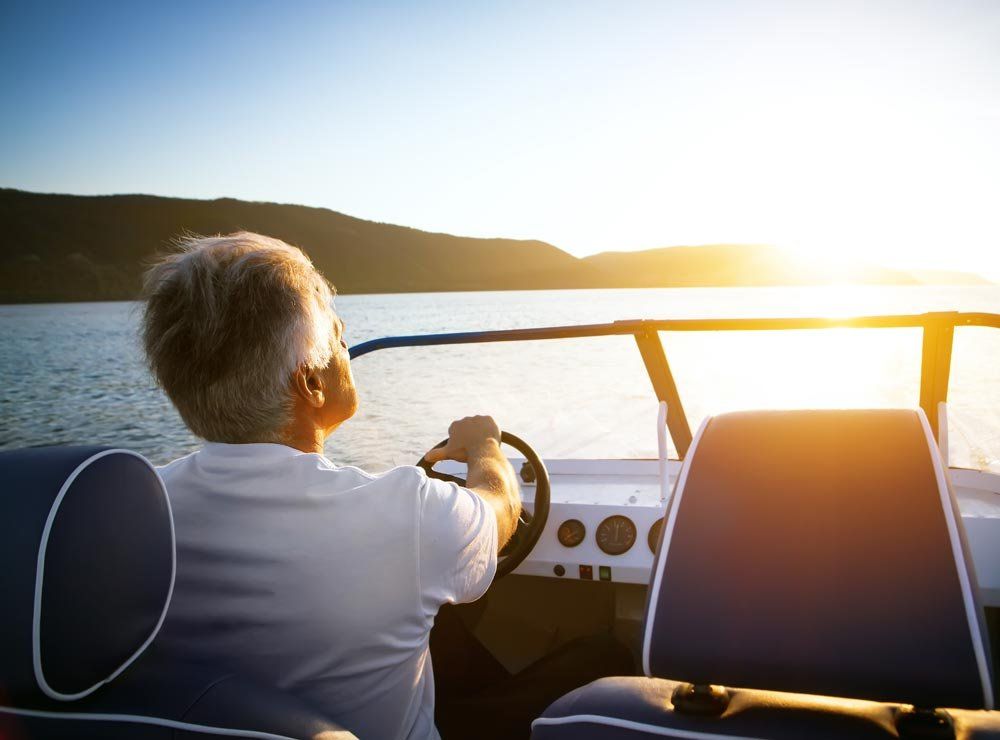 Volwassen man in een speedboot met mechanisch stuursysteem bij schemering